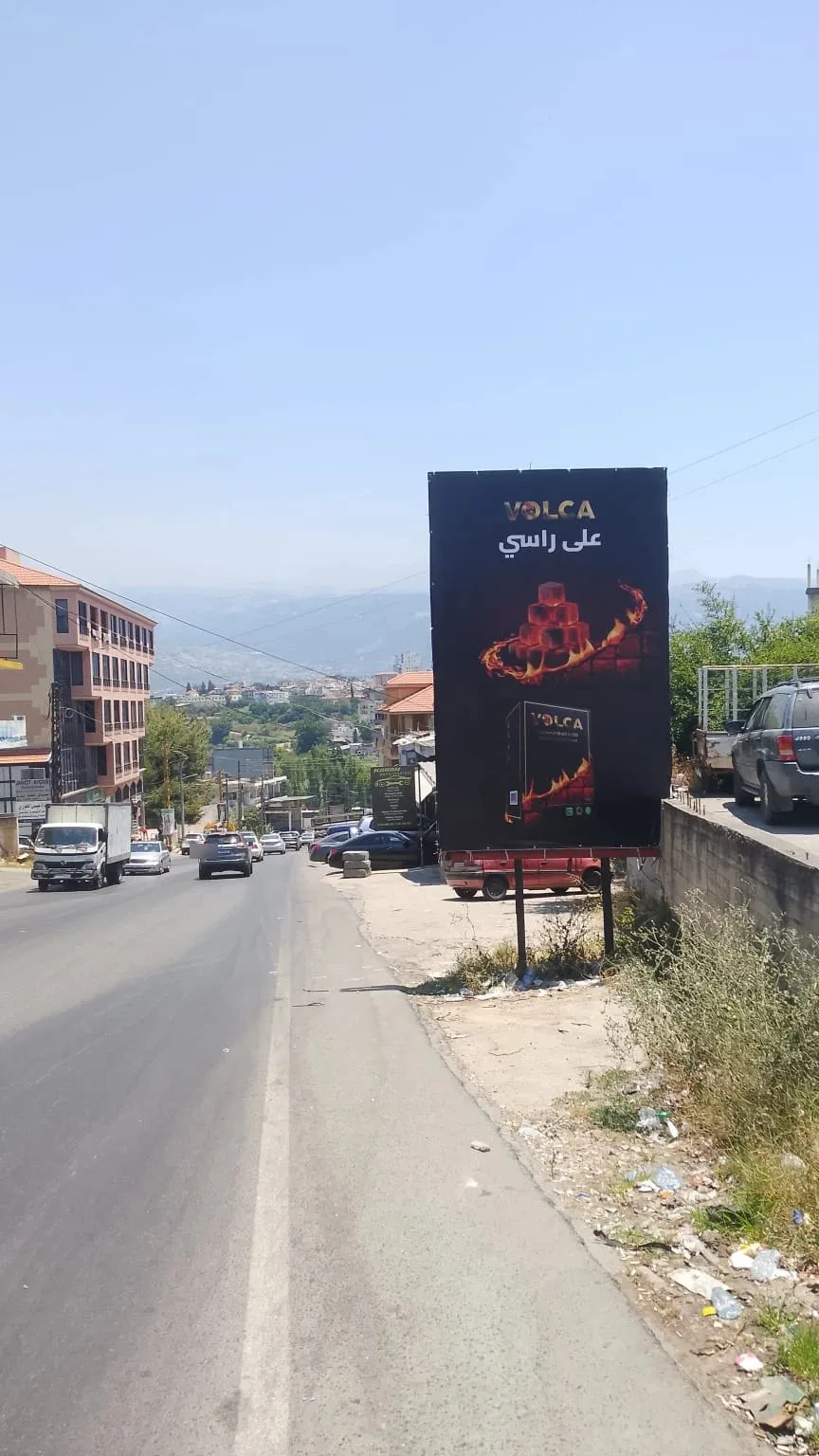 Volca portrait billboard beside a hillside road, على راسي